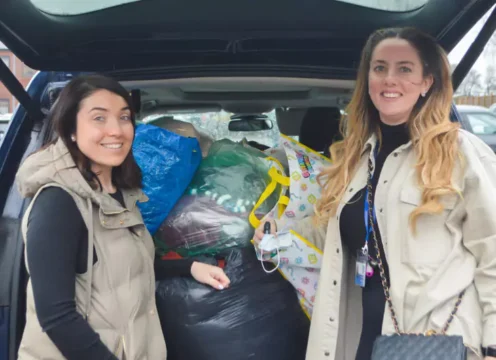 Two women are stood next to clothes donated to Ukraine refugees.