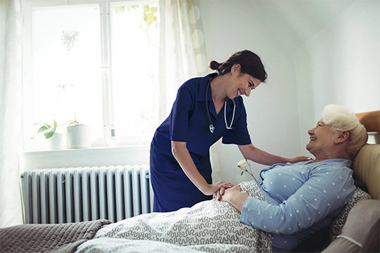 Carer assisting an elderly client in bed