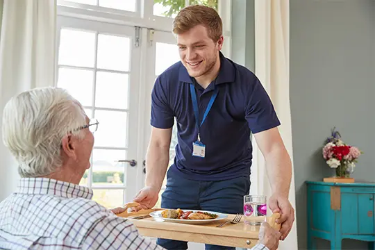 Lunch being served to an elderly client by a happy carer